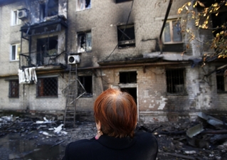 Žena u obytných domů v Doněcku zasažených čerstvou ukrajinskou střelbou.