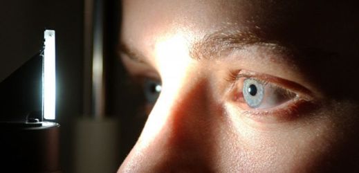 Pacient sedí u přístroje jako při vyšetření zraku u očního lékaře (ilustrační foto). 