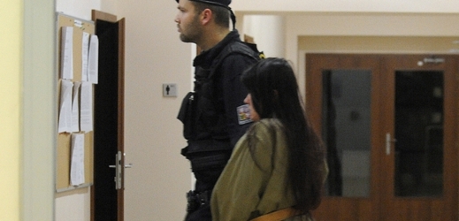 Policista přivádí útočnici k soudu.