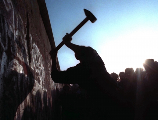 Německo si připomnělo pád Berlínské zdi. Na archivním snímku z roku 1989 je zachycen muž, který se snaží zeď probourat.