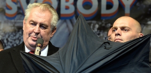 Člen ochranky kryje prezidenta Zemana deštníkem před letícími předměty na pražském Albertově.