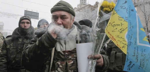 Muž v ulicích Kyjeva s ukrajinskou vlajkou.