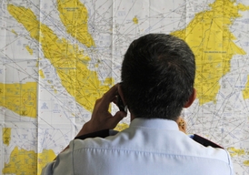 Pracovník letiště si prohlíží mapu v souvislosti se zmizením letadla AirAsia.