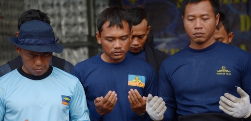 Indonéští potápěči se modlí za úspěšné vyzdvihnutí trosek letounu.