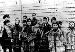 Děti za ostnatým drátem koncentračního tábora Osvětim na snímku z ledna 1945 po osvobození tábora Sověty.