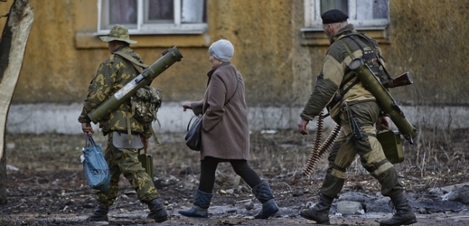 Žena jde mezi ozbrojenými ruskými vojáky v Debalceve.