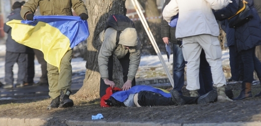 Muž zakrývá ukrajinskou vlajkou oběť výbuchu v Charkově.