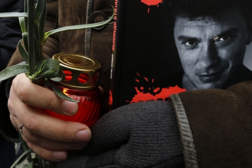 Muž drží svíčku a magazín "The New Times," na jehož obálce je Němcov vyobrazen.