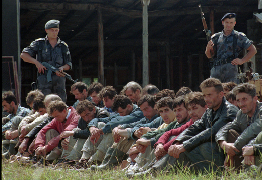 Dva srbští strážníci hlídají skupinu bosenských Muslimů z enklávy Srebrenica v srbském městě Uzice. Srpen 1995.