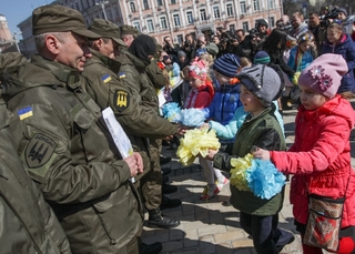 Na frontu. Děti dávají v Kyjevě pugéty dobrovolníkům praporu Donbas.