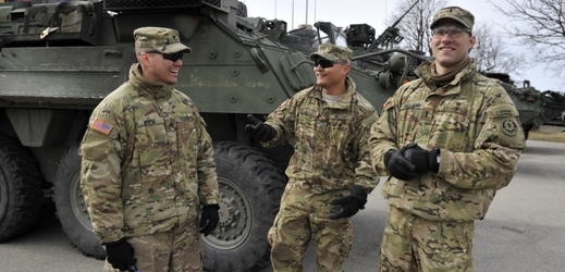 Američtí vojáci stojí před transportérem Stryker.