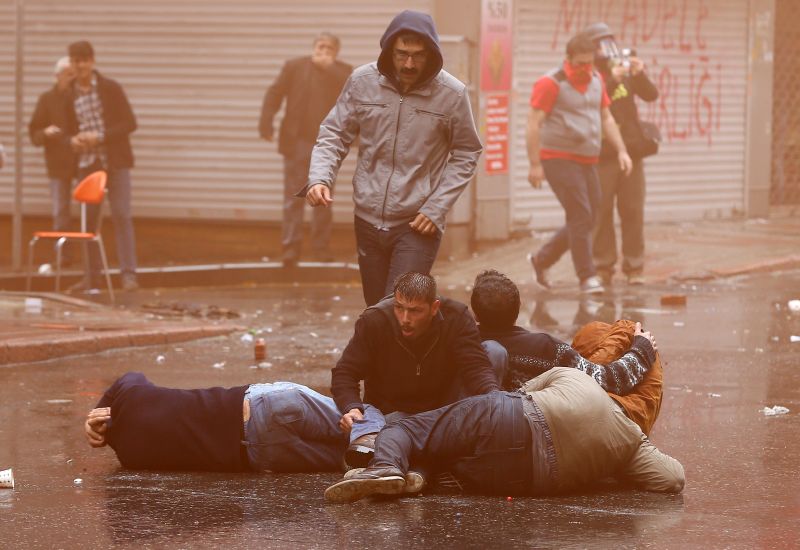 Demonstranté v Turecku se brání před proudem vody, kterým se policisté snažili rozehat dav.