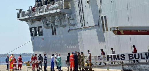 Migranti vystupují z britské námořní lodi v italském přístavu Taranto.