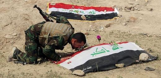 Voják se uklání na místě masového hrobu iráckých vojáků zavražděných po obsazení Tikrítu.