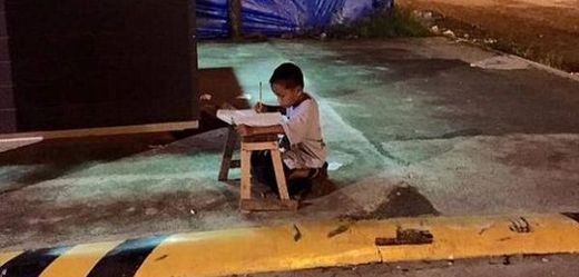 Devítiletý Daniel na snímku píše domácí úkoly pod světlem restaurace McDonald.