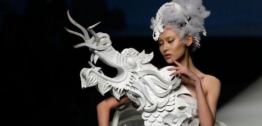 Modelka prezentuje šaty s drakem od Xu Minga na festivalu módy China Fashion Week v Pekingu.