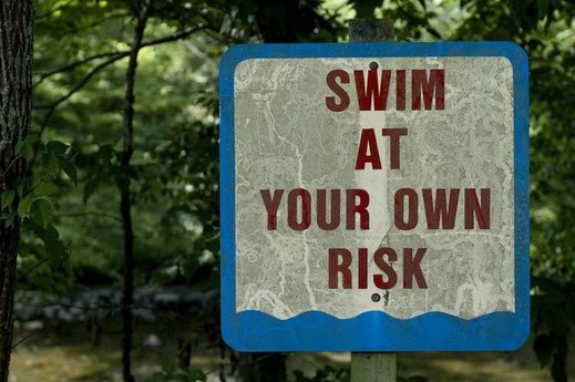 Tabule upozorňující na plavání na vlastní nebezpečí.