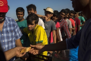 Uprchlíci čekají před opuštěným hotelem na ostrově Kos na jídlo.