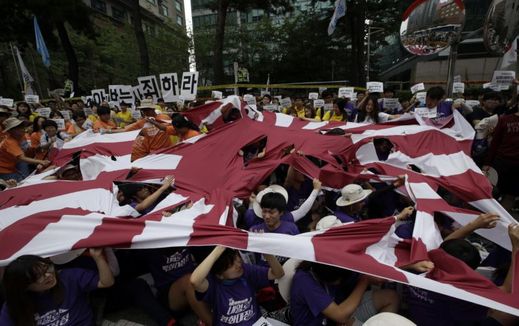 Jihokorejští studenti trhají japonskou vlajku jako nesouhlas s projevem premiéra Abeho.