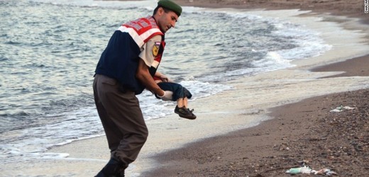 Turecký policista odnáší tělo utopeného chlapce.