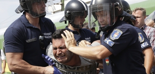 Migrant v sevření maďarských policistů.