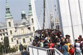 Stovky uprchlíků jdou v Budapešti po mostě před Dunaj, míří pěšky do Rakouska.