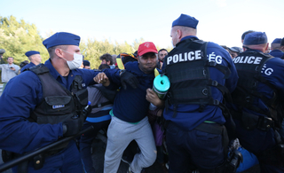 Maďarská policie se snaží zadržet běžence v přijímacím centru.