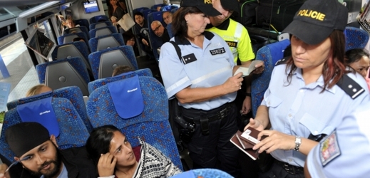 Policisté kontrolují uprchlíky ve vlaku.