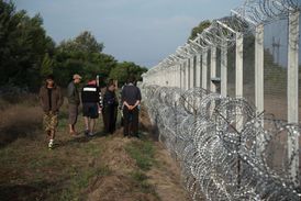 Uprchlíci procházející se podél plotu označujícím hranici mezi Srbskem a Maďarskem v srbském pohraničním městě Horgos.