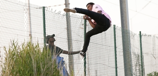Uprchlíci přelézají plot v Calais (ilustrační foto).