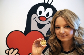 Ředitelka Nadace Zdeňka Milera Karolína Milerová ukazuje zlatou medaili s portrétem výtvarníka Zdeňka Milera a s postavičkou Krtka.