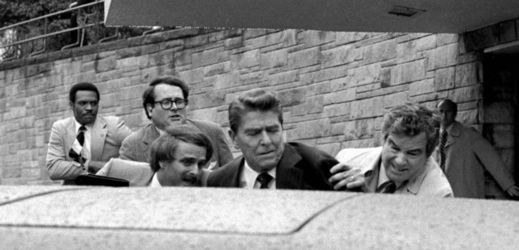Atentát na Ronalda Reagana. Jerry Parr (vpravo) tlačí amerického prezidenta do limuzíny.