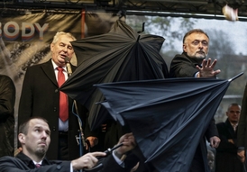 Prezident Miloš Zeman je kryt deštníky během oslav výročí sametové revoluce 17.11.2014.