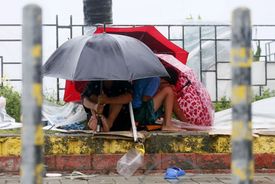 Malí Filipínci se chrání před silným deštěm.