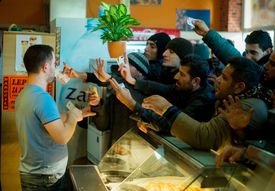 Běženci si chtějí koupit jídlo v kiosku na slovinsko-rakouských hranicích.