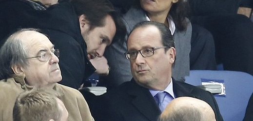 Snímek nejspíš zachycuje moment, kdy je prezident Francie Francoise Hollande informován při sledování fotbalového zápasu Francie - Německo o útocích teroristů.