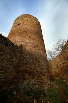 Turisté pózují na středověkých hradbách zříceniny Valdek a gotické zdivo se jim drolí pod nohama.