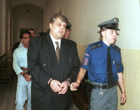 1996. Jonák přichází v doprovodu eskorty na jednání o případu vraždy jeho manželky.
