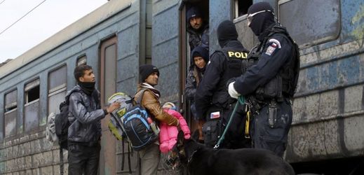 Uprchlíci nastupují do vlaku směřujícího do Srbska, zatímco policisté České republiky udržují pořádek na platformě v tranzitním centru pro uprchlíky v blízkosti jižního makedonského města Gevgelija.