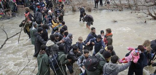 Uprchlíci se brodí řekou.
