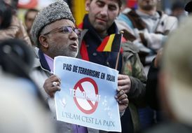 Muž po útoku v ulicích Bruselu drží transparent proti teroristům. Nenávist vůči islámu v Evropě rapidně roste.