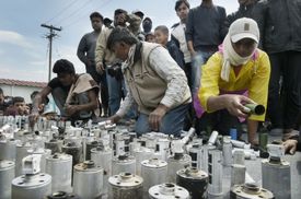 Migranti ukazují lahve od slzného plynu, který proti nim byl použit.