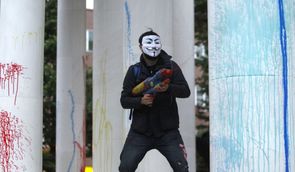 Demonstrant s vodní pistolí naplněnou barvou.