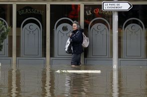 Žena hledající cestu zatopenou ulicí.