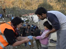 Česká dobrovolnice rozdává oblečení a dětem sladkosti v uprchlickém táboře Moria.