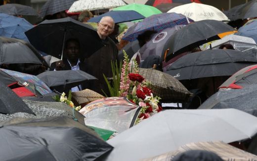 Mezi deštníky byly vidět květiny k uctění památky zavražděného kněze.
