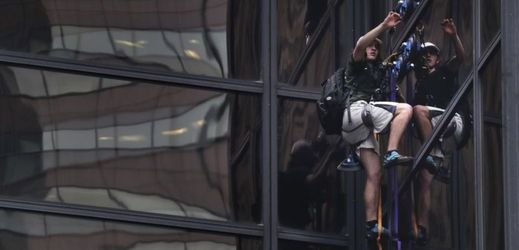 Snímek muže lezoucího po povrchu mrakodrapu.
