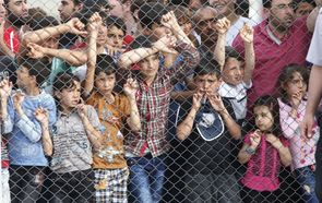 Migranti stojí za plotem a vyhlížejí kancléřku při návštěvě Turecka.