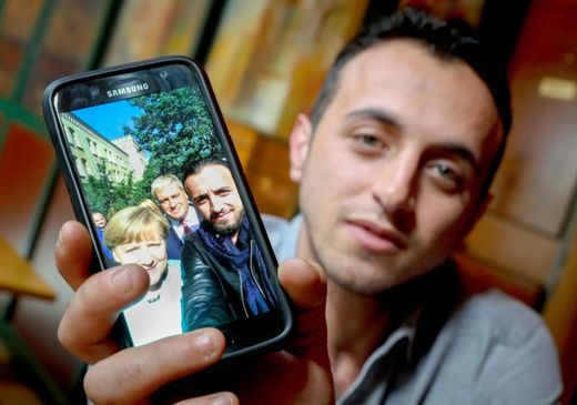 Syrský uprchlík Rodin Saouan ukazuje slavné selfie, jež si pořídil s kancléřkou Merklelovou.