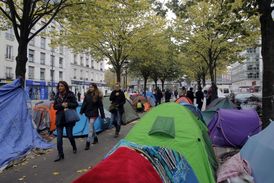 Snímek ze situace v Paříži, lidé chodí mezi stany v provizorním táboře.